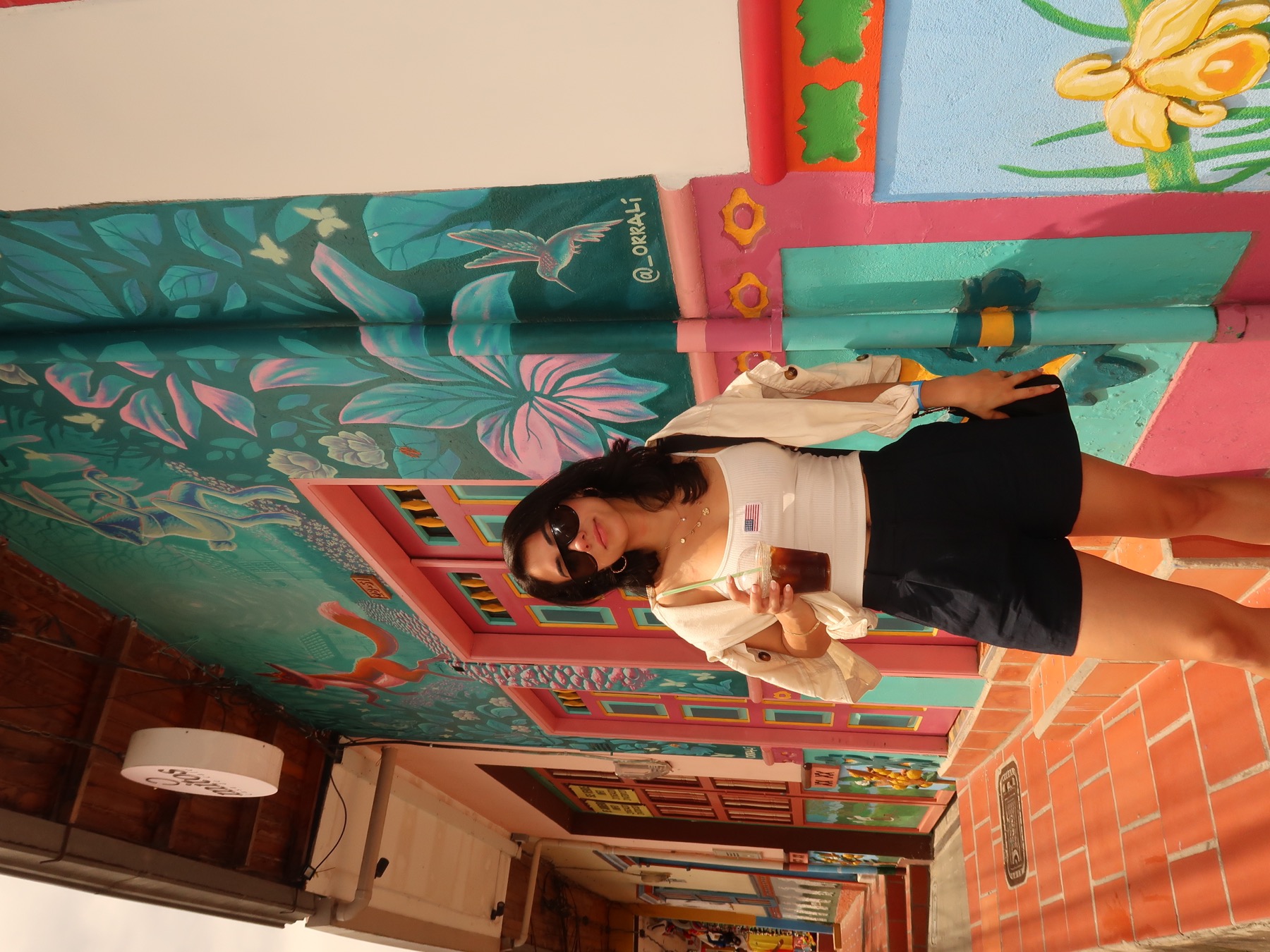 Jasmin exploring a colorful street with an iced coffee